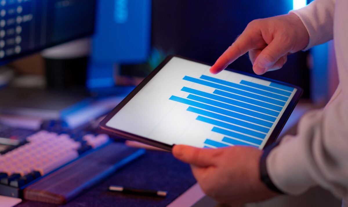 À propos Business professional analyzing bar chart on tablet in office setting, highlighting data insights.